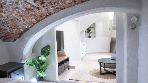 Une chambre avec un mur en briques, un lit, un bureau et une plante en pot.