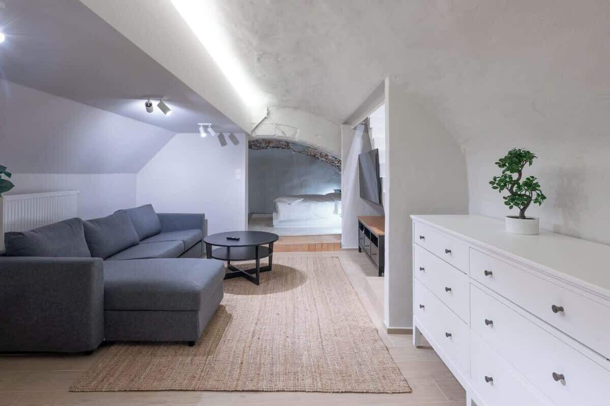 Una sala de estar moderna con un sofá gris, una mesita redonda y un aparador blanco.