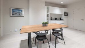 Une cuisine moderne avec des meubles blancs, une table à manger en bois et deux chaises noires.