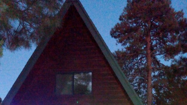 Une cabane en bois dotée d’un patio couvert, d’une porte-fenêtre coulissante et d’une chaise à l’extérieur.