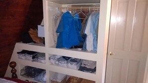Un placard avec des vêtements suspendus et des bacs de rangement.