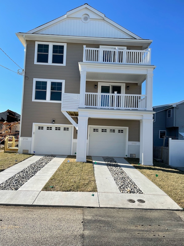 A two-story house with a garage, a balcony, and a well-maintained lawn.