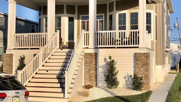 A two-story house with a front porch, a staircase leading to the entrance, and a driveway. - Beautiful Newer Construction 5 BR 3.5 bath (Ocean City)