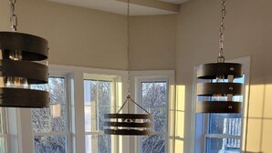 A spacious kitchen with a large island, a dining table, and chairs. There are large windows providing a view of the outside. - Beautiful Newer Construction 5 BR 3.5 bath (Ocean City)