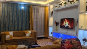 A living room with a sofa, a coffee table, and a TV mounted on the wall. - Beautiful serene home with lake view (Nakuru)