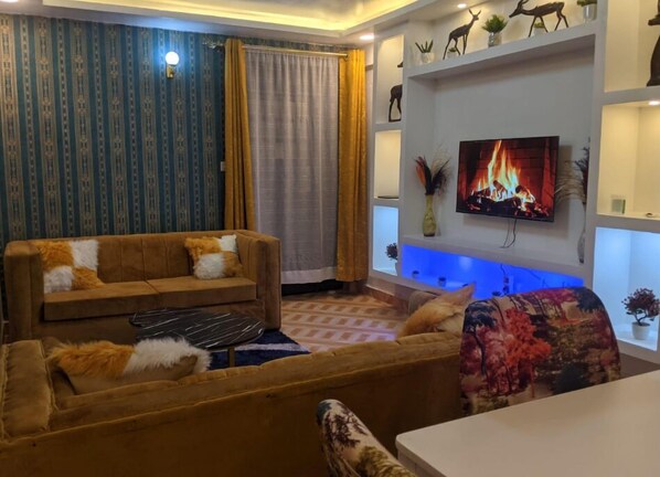 A living room with a sofa, a coffee table, and a TV mounted on the wall.