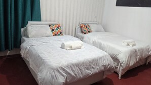 A hotel room with two beds, each with white linens and colorful pillows. - Beautiful serene home with lake view (Nakuru)