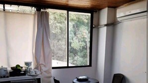 Una stanza con un letto, una piccola scrivania, due sedie, un tavolo e una finestra con tende.
