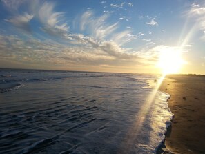 A beach with waves and a sunset.