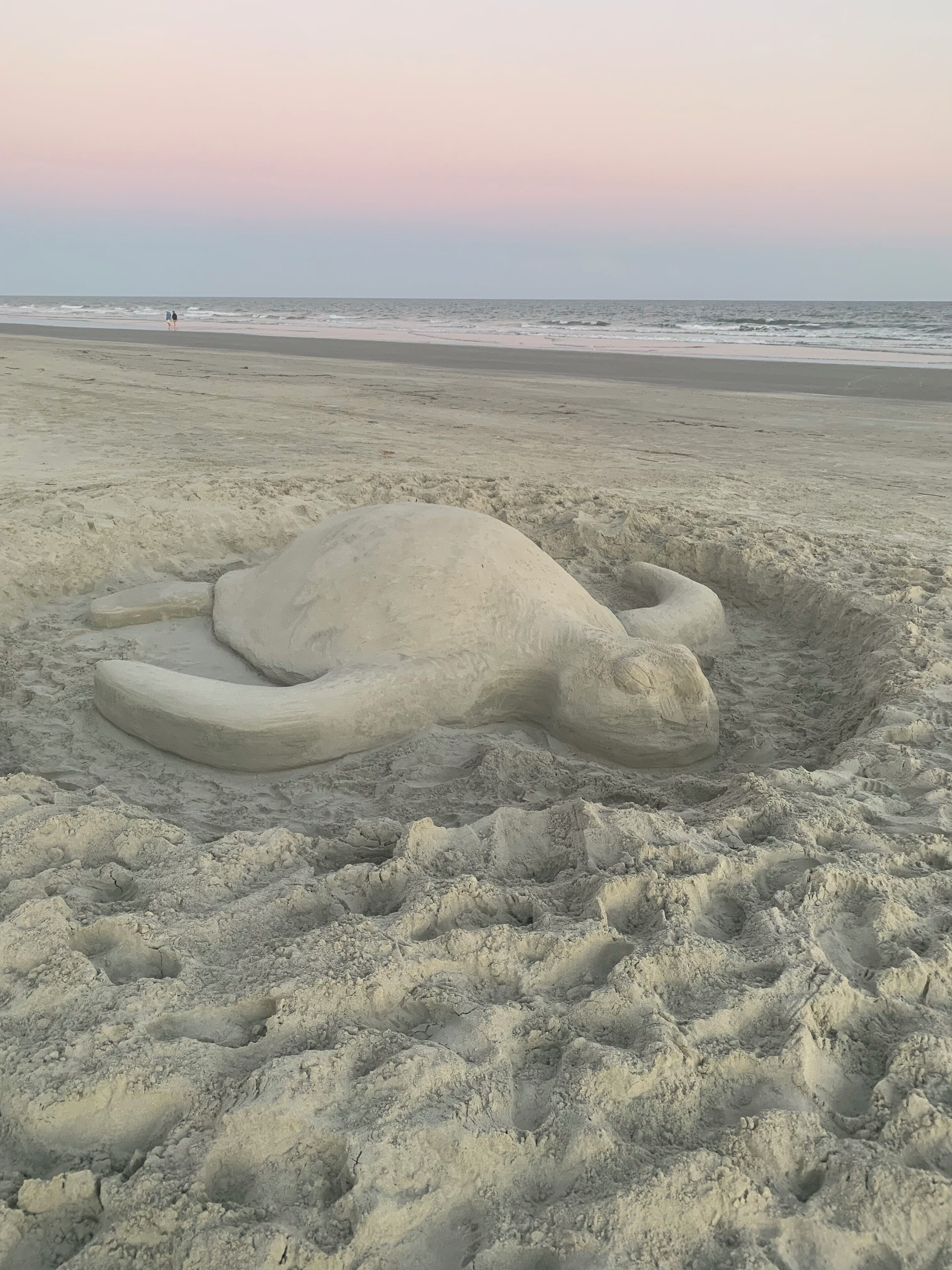 Une grande sculpture de sable représentant une tortue de mer, sur une plage.