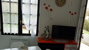 A dining area with a table, chairs, a clock, and a desk with a computer. - Maison ds Marais Poitevin (Taugon)