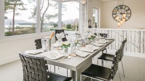 Un comedor con una mesa larga dispuesta para seis personas, ventanas amplias y vistas al exterior.