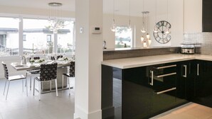 Cocina moderna con armarios negros, una isla grande, luces colgantes y un reloj en la pared.