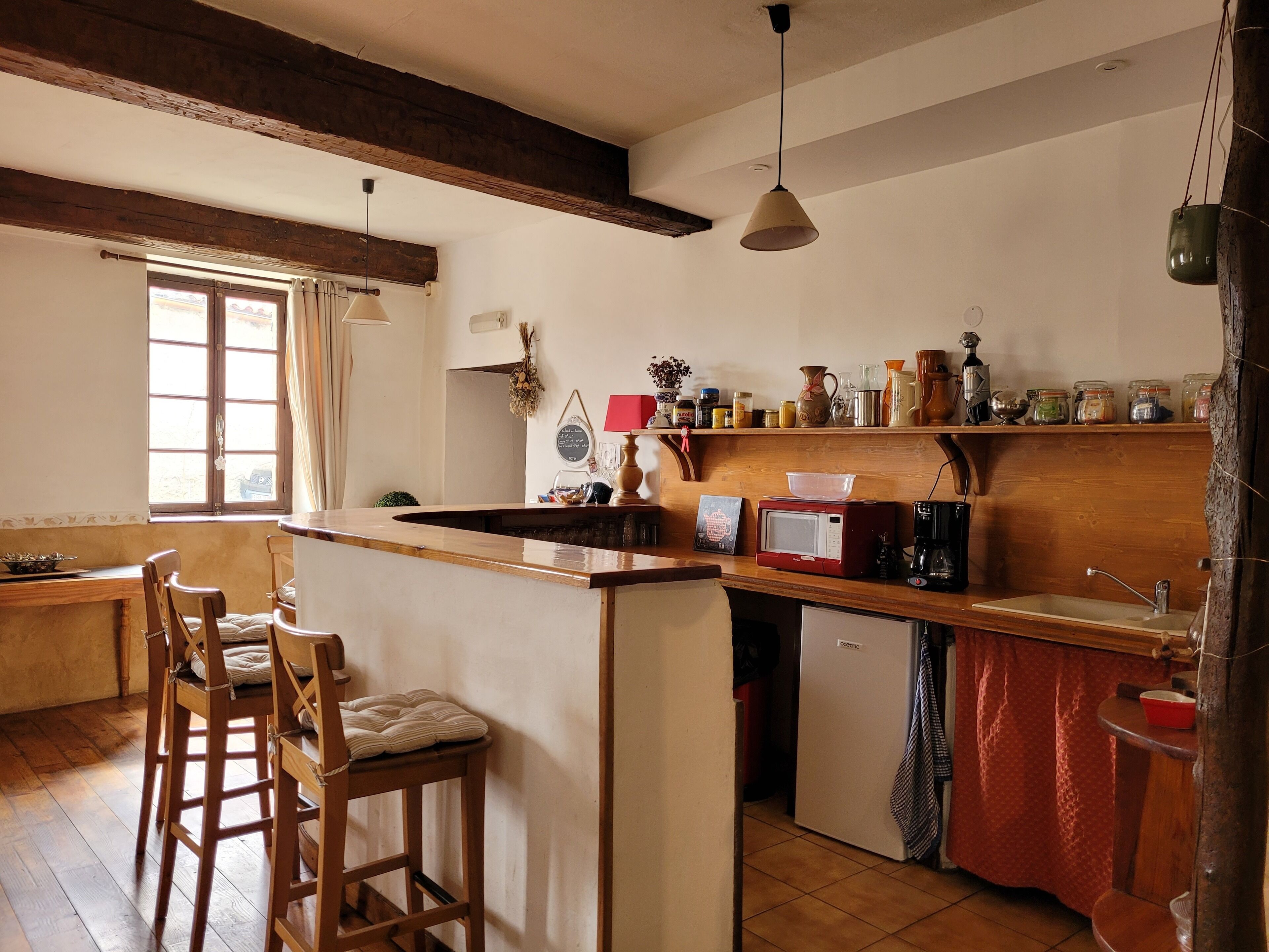 A kitchen with a wooden island, bar stools, a refrigerator, a microwave, and a sink.