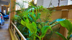 A parking area with a blue car, surrounded by lush green plants and a wooden fence. - CherryWood Apartments (Nairobi)