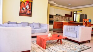 A living room with a sofa, a coffee table, and a painting on the wall. - CherryWood Apartments (Nairobi)