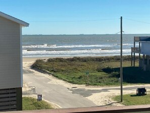 A beach view with a road leading to a building, a signpost, and a utility pole. - Mar Y Sol: 4  BR, 3  BA House in Port Bolivar, Sleeps 16 (Port Bolivar)
