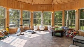 A wooden interior with large windows, a ceiling fan, exercise equipment, and a pool table. - Cozy cottage home close to nature includes game room, fitness equip, & Hot Tub. (Portland)