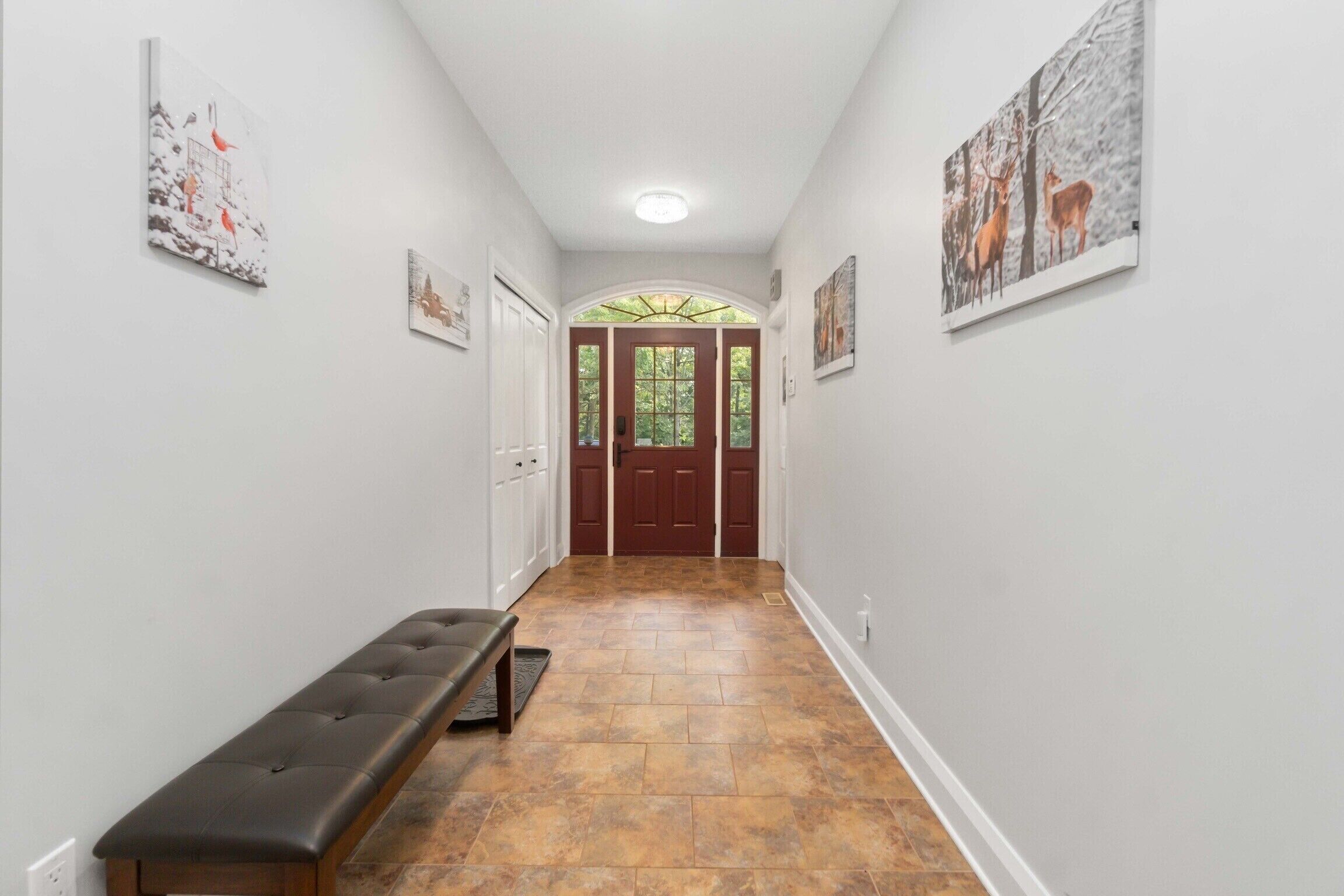 A hallway with a bench, a door, and framed pictures on the walls.