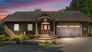 A two-story house with a dark green exterior, a red front door, and a garage. - Cozy cottage home close to nature includes game room, fitness equip, & Hot Tub. (Portland)