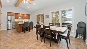 A spacious kitchen with wooden cabinets, a stainless steel refrigerator, and a dining area with a large table and chairs. - Cozy cottage home close to nature includes game room, fitness equip, & Hot Tub. (Portland)