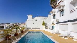 A rooftop pool with a view of the city, surrounded by potted plants and lounge chairs. - Clube do Monaco Stunning Beachfront Apartment Overlooking Town (Albufeira)