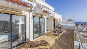 A rooftop terrace with a dining area, sliding glass doors, and a view of the sea. - Clube do Monaco Stunning Beachfront Apartment Overlooking Town (Albufeira)