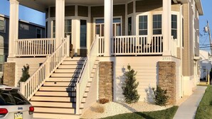 A two-story house with a front porch, a staircase leading to the entrance, and a driveway. - Luxury Newer construction -5BR 3.5 bath  2nd floor (Ocean City)