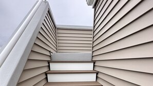 A set of wooden steps leading up to a landing, surrounded by siding panels. - Luxury Newer construction -5BR 3.5 bath  2nd floor (Ocean City)