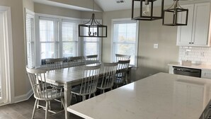 A spacious kitchen with a large island, white cabinetry, and a dining area with a wooden table and chairs. - Luxury Newer construction -5BR 3.5 bath  2nd floor (Ocean City)