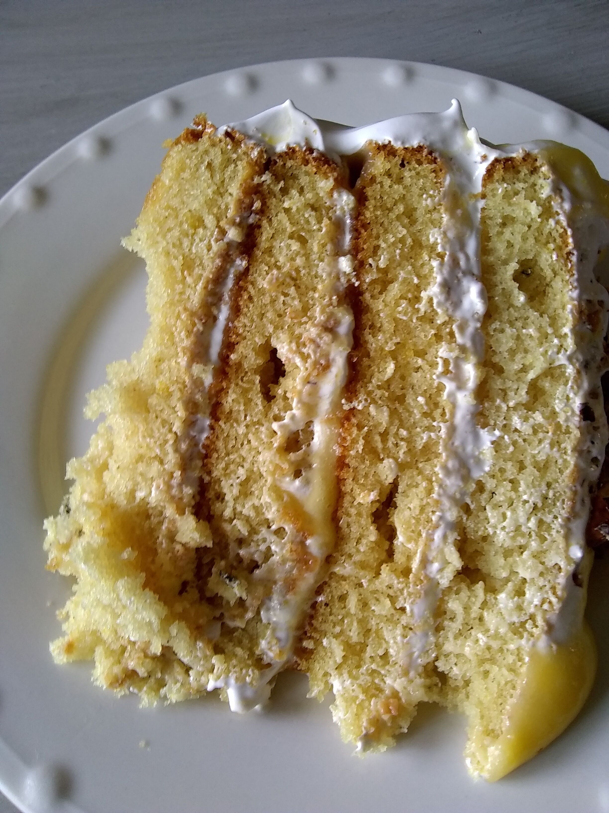 A slice of cake with white icing on a plate.