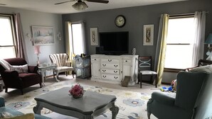 A living room with a television, a clock, and a floral rug.
