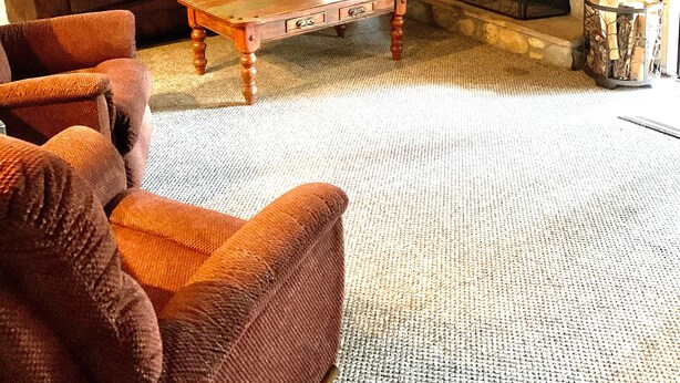 A cozy living room with a stone fireplace, a dark brown sofa, and a wooden coffee table. - Sports Village Lower Unit Comfy Mountain Retreat (Pinetop)