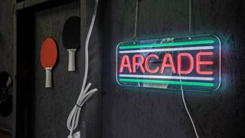 Een neonbord met de tekst 'ARCADE' op een structuurrijke muur, met twee pingpongbats aan de linkerkant.