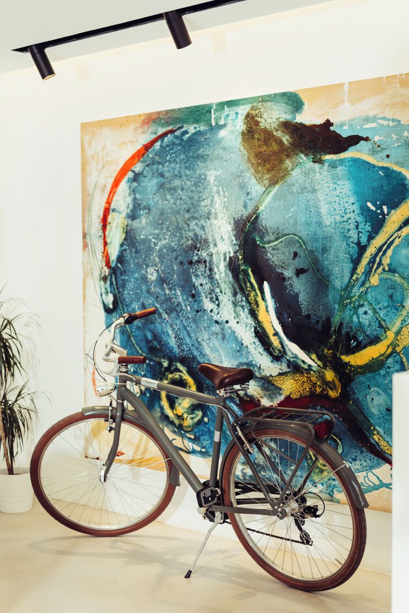 A bicycle parked in front of a large abstract painting.