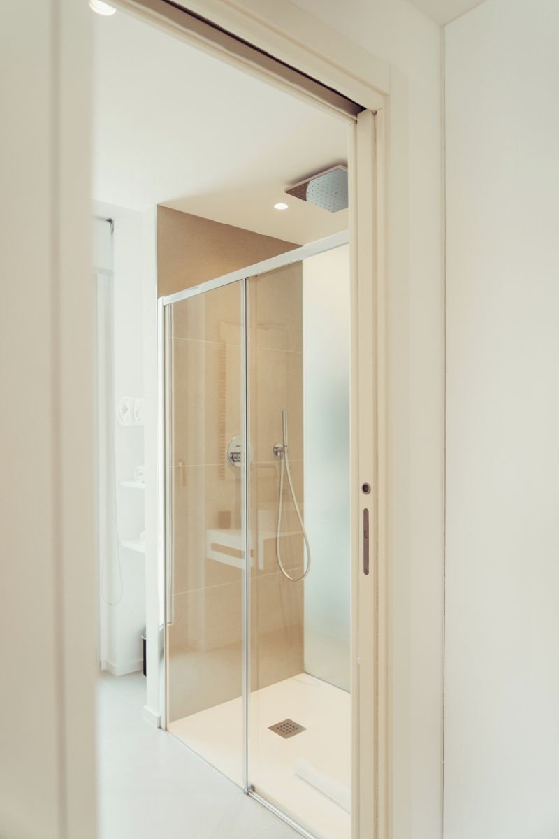 A modern bathroom with a glass shower enclosure, a white sink, and a toilet.