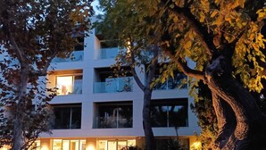 A modern multi-story building with a well-lit entrance and a pathway leading to the main entrance.