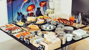 A buffet with various food items and beverages, including fruits, pastries, and a juice bar.