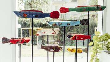 Un grupo de decoraciones con forma de pez, de colores variados, colgando de una ventana.