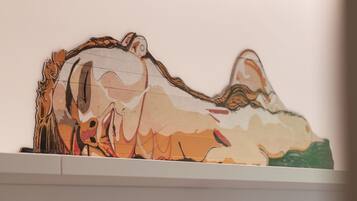 A wall-mounted artwork depicting a stylized animal figure.