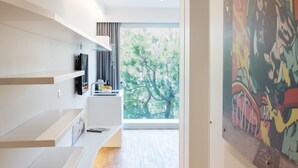 A modern kitchen with white cabinetry, a built-in oven, and a window overlooking a tree.