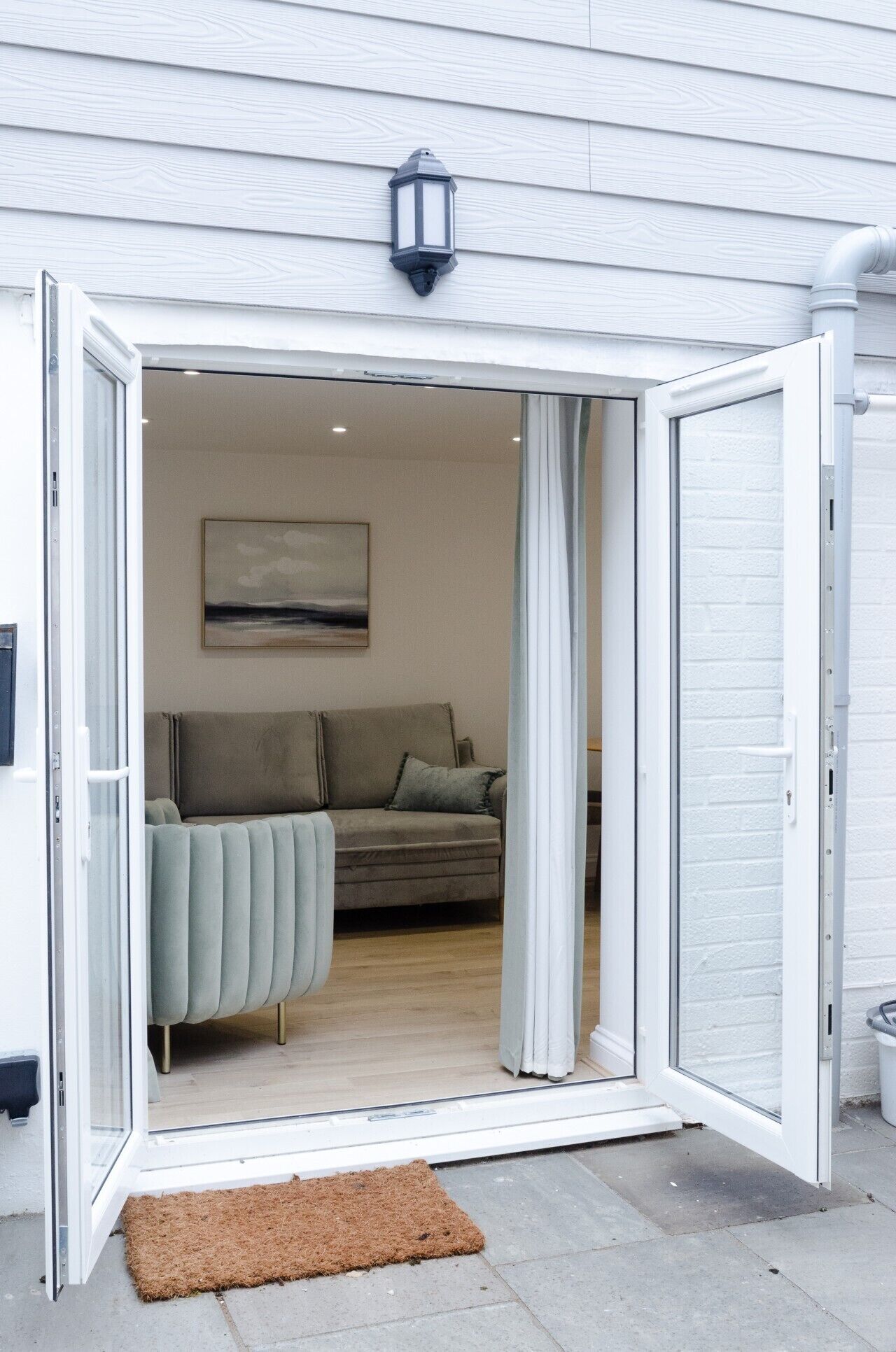 An open door leading to a living room with a sofa and a painting on the wall.