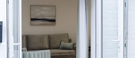 An open door leading to a living room with a sofa and a painting on the wall.