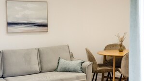 Una sala de estar moderna con un sofá, una mesa de comedor con sillas y un cuadro en la pared.