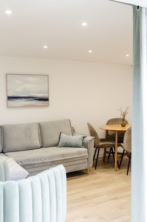 Una sala de estar moderna con un sofá, una mesa de comedor con sillas y un cuadro en la pared.