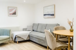 Una sala de estar moderna con un sofá gris, una mesa redonda de madera y un radiador.