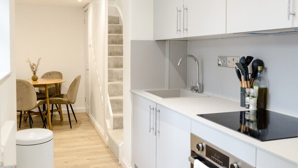 Een moderne keuken met witte kasten, een zwart aanrecht en een roestvrijstalen spoelbak.