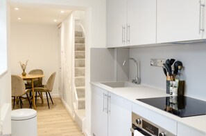 Cocina moderna con armarios blancos, encimera negra y pileta de acero inoxidable.