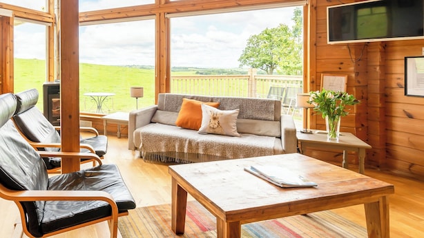 A cozy room with a large window, a sofa, a table, and a TV. - 2 bedroom accommodation in Linlithgow, near Edinburgh (Linlithgow, near Edinburgh)