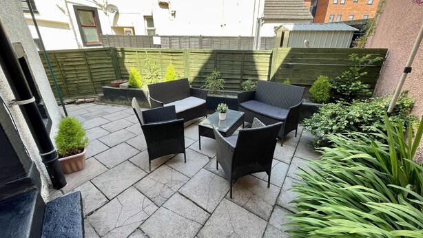 A patio with outdoor furniture, a small table, and potted plants. - The Oaks Cottage (Penrith)